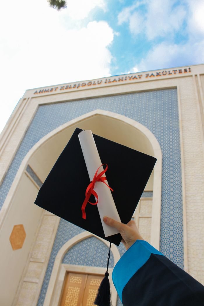 Home Celebrating graduation with a diploma and cap in front of a university.
