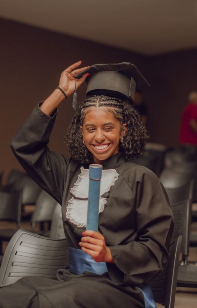 Smiling graduate woman holding diploma in a vibrant indoor ceremony.
